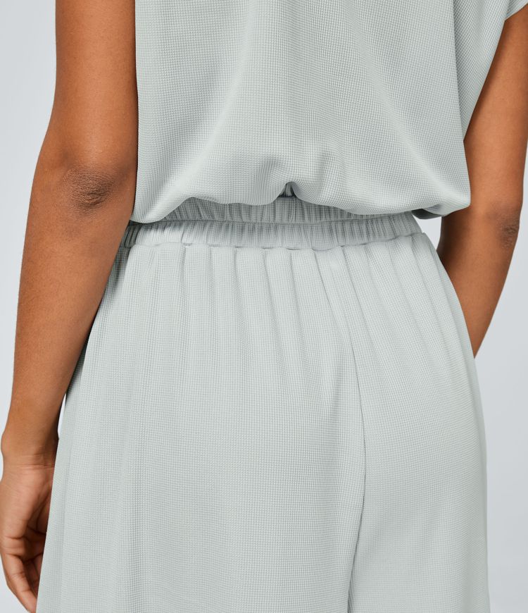 Jumpsuit™ - Tuta con scollatura a V, maniche corte, tasche laterali a pieghe e gamba larga, motivo a onde fluide.